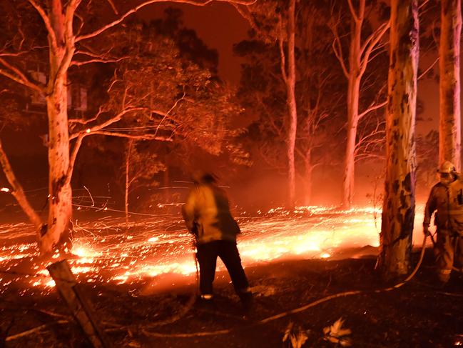 Firefighters hose down trees as they battle against bushfires around the town of Nowra in the Australian state of New South Wales on December 31, 2019. - Thousands of holidaymakers and locals were forced to flee to beaches in fire-ravaged southeast Australia on December 31, as blazes ripped through popular tourist areas leaving no escape by land.Picture: Saeed Khan/AFP