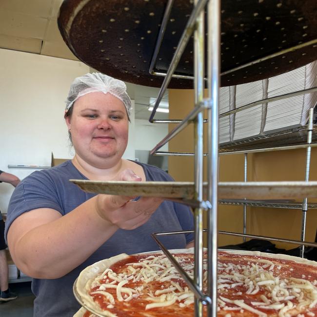 Rachelle Edgar loads fresh pizza bases into a tower, at Say Cheese Pizza, Bendigo. Picture: Julieanne Strachan