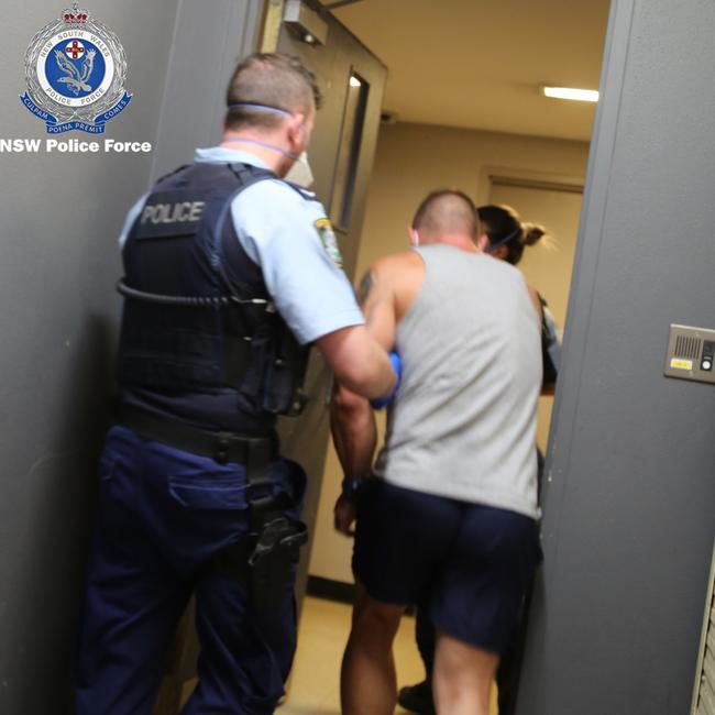 A masked policeman taking Bekiri into custody