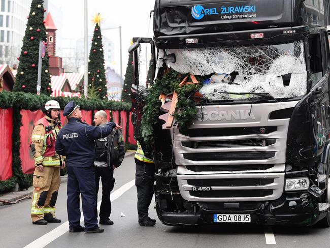 A policeman and firemen stand next to a truck at the scene where it crashed into a Christmas market near the Kaiser Wilhelm Memorial Church in Berlin. Picture: AFP/Tobias Schwarz