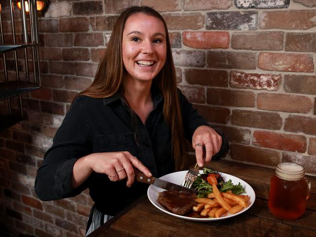 Meanwhile, Kelsey Reohr digs into one of Sydney’s cheapest steaks at Donny's Bar in Manly, where the cost is $5 when purchased with an alcoholic drink. Picture: Toby Zerna