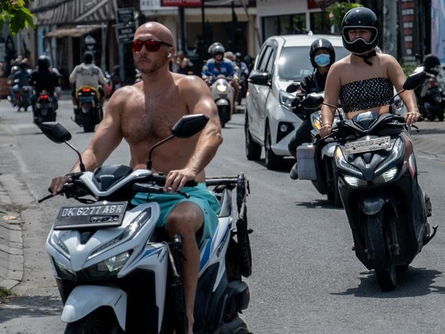 CANGGU, BALI, INDONESIA - MARCH 26: A foreigner tourist rides a motorcycle without helmet and shirt at a main road on March 26, 2023 in Canggu, Bali, Indonesia. Indonesian island of the gods plans to enact some rules for foreign tourists on operating motorcycles, scooters, and cars for travel around the island following a number of violations of traffic rules and bad behavior such as riding motorcycles without valid paperwork and helmets, driving recklessly, using fake Indonesian ID cards or abusing residence and work permits. (Photo by Agunng Parameswara/Getty Images)