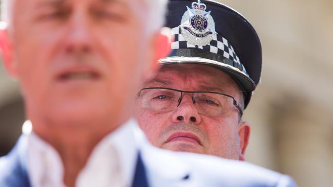 Victoria Police Chief Commissioner Graham Ashton, pictured behind Prime Minister Malcolm Turnbull at a tribute for the Bourke Street victims, should resign, writes Miranda Devine. (Pic: Paul Jeffers/Getty Images)