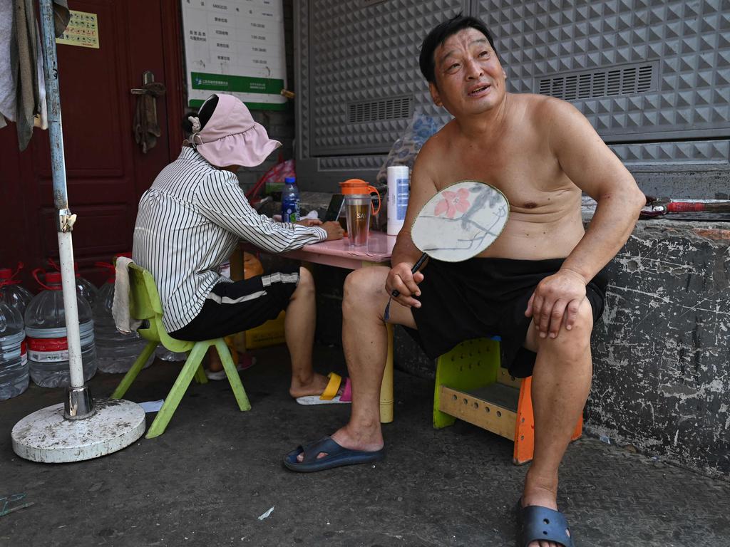 A man fans himself while taking a break in an alley during heatwave conditions in Beijing. Picture: Greg Baker/AFP