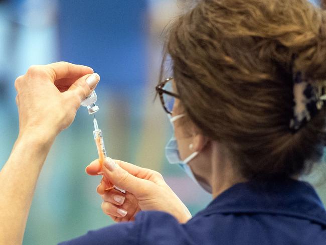 A nurse prepares a dose of the Oxford/AstraZeneca Covid-19 vaccine at a mass vaccination centre at Epsom Downs Racecourse in Epsom, southern England on January 11, 2021. - Seven mass coronavirus vaccination sites opened across England on Monday as the government races to dose millions of people while a new strain of the disease runs rampant across the country. The sites include football stadiums and a horse racing course, and are located in cities including Bristol, London, Newcastle and Manchester. (Photo by Dominic Lipinski / POOL / AFP)