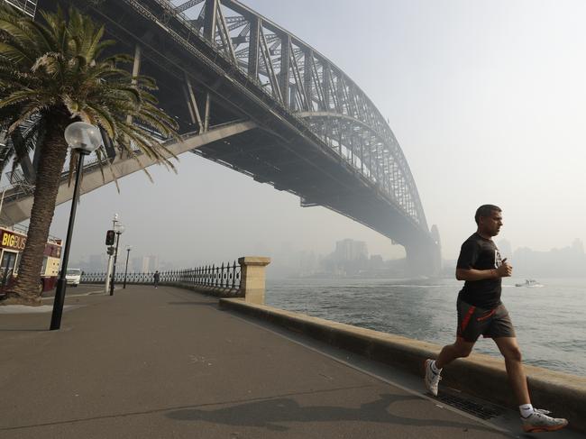 A man jogs under the Sydney Harbour Bridge as a smoke haze hangs over Sydney. Picture: AP