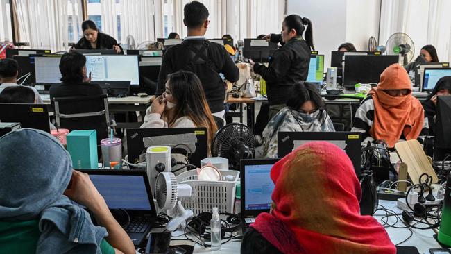 Workers sit at their desks during a raid by agents of the Presidential Anti-Organised Crime Commission (PAOCC) and the National Bureau of Investigation at an office of a suspected online scam farm in Manila on January 31, 2025. Philippine authorities arrested around 100 people on January 31 in a raid on a suspected online scam farm in Manila they said extorted victims. Picture: Jam Sta Rosa / AFP