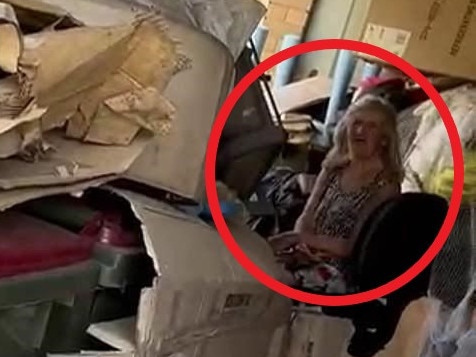 A woman who slept with her brother’s dead body for years in a rat-infested 'house of horrors' has been filmed back in the garage hours after the discovery.