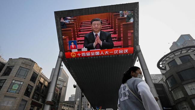 An outdoor screen shows a live news coverage of President Xi Jinping during the opening session of the National People's Congress (NPC) at the Great Hall of the People.