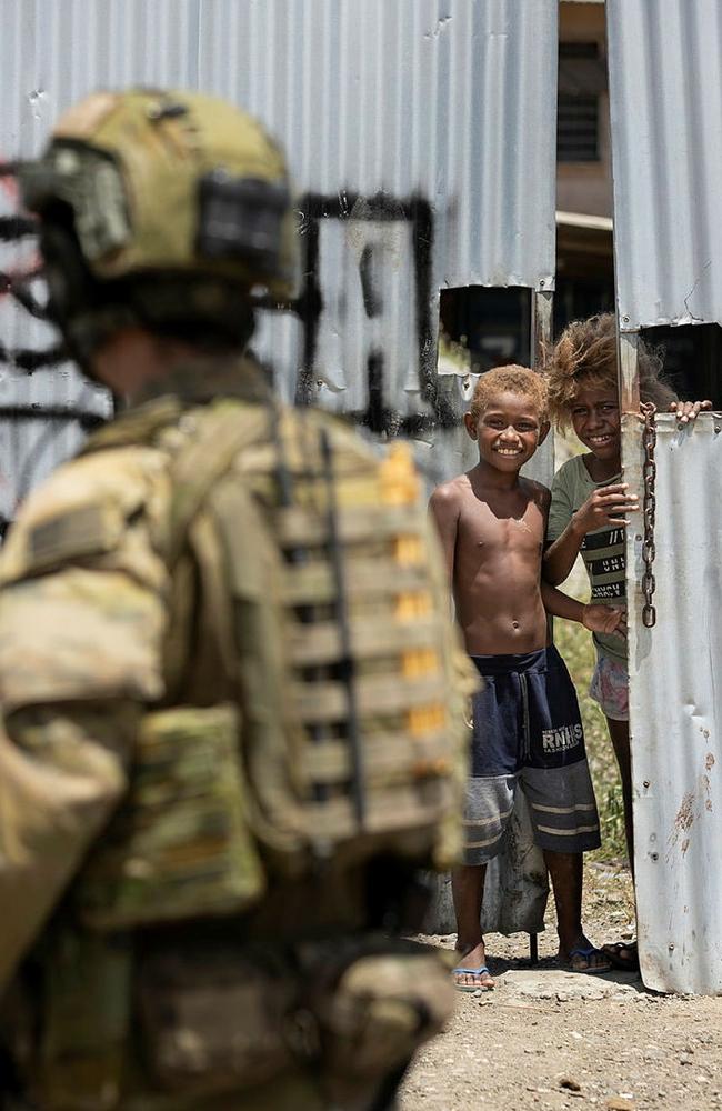 Australian Army Corporal Aaron Woodham from the Joint Task Group 637.3 is greeted by a local child during a patrol though Honiara, Solomon Islands. Picture: Supplied