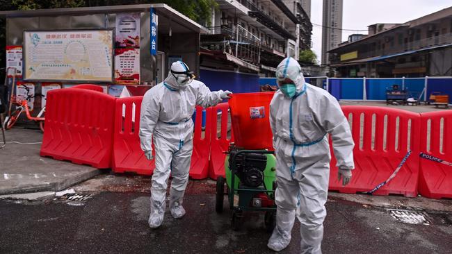 Workers wearing protective suits walking next to the Huanan Seafood Wholesale Market in Wuhan, in China's central Hubei province, in March. Picture: AFP