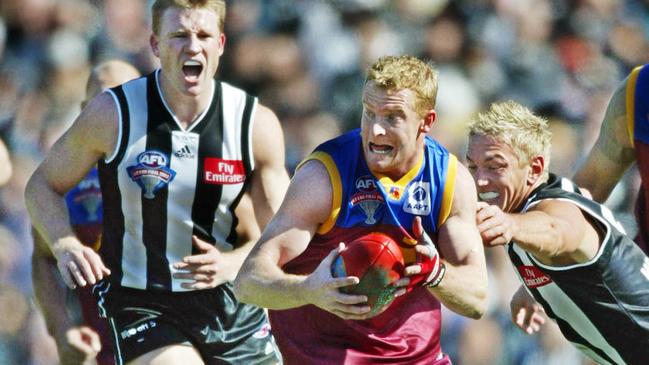 Michael Voss breaks a Shane Woewodin tackle as Nathan Buckley looks on during the 2003 Grand Final.