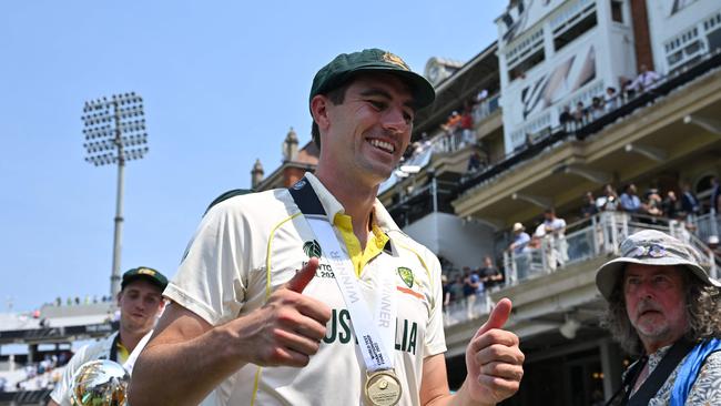 Australia's Pat Cummins (C) is on top of the world. (Photo by Glyn KIRK / AFP)