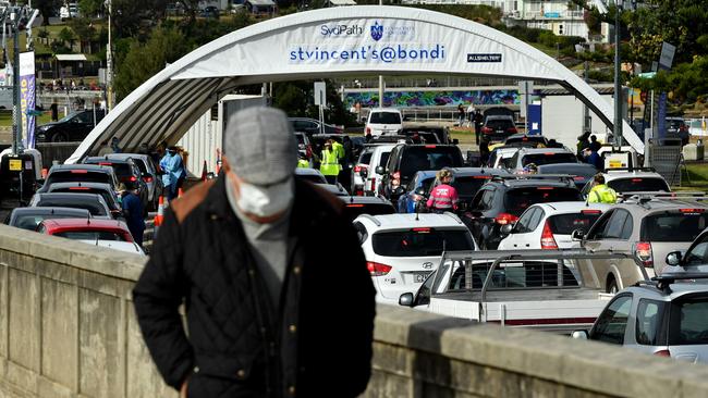 A man walks along the front as hundreds of cars queue up for testing. Picture: NCA NewsWire/Joel Carrett