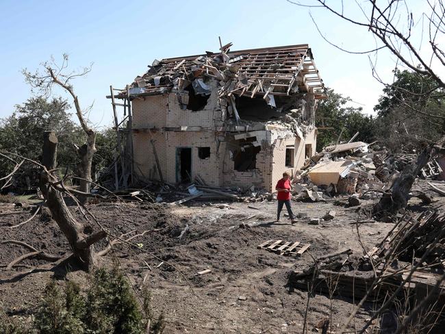 A local resident walks past a crater and a destroyed residential house following a missile strike in Kyiv region. Picture: AFP