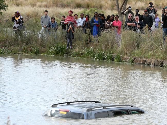 HS25 A large group watches on as police divers prepare to remove Akon Guode's who's car after it plunged into a lake off Manor Lakes Boulevarde. Picture: Mark Stewart