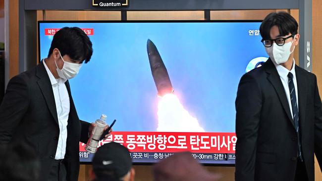 People walk past a television screen showing a news broadcast with file footage of a North Korean missile test, at a railway station in Seoul on October 4, 2022. Picture: AFP