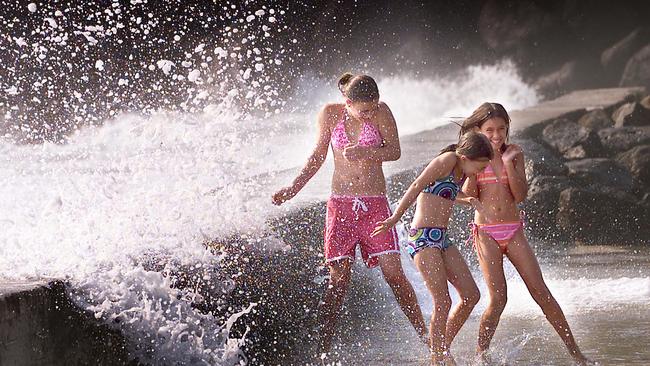 (L-R) Elise Cooper 13, Siobahn Davey 9, and Sian Cooper 11 at Snapper Rocks dodge the spray from breaking waves. Picture: Adam Ward