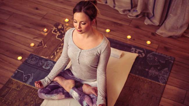 Adult caucasian woman practicing yoga exercise at home. Soft light, candles, brick wall in background. Picture: petrunjela