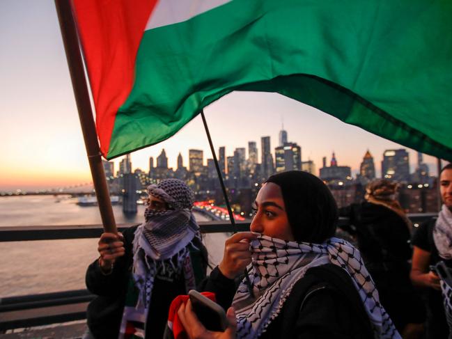 TOPSHOT - Demonstrators hold Palestinian flags as they march through Brooklyn Bridge during a rally in support of Palestinians in New York City on November 7, 2023. Thousands of people, both Israeli and Palestinians, have died since October 7, 2023, after Palestinian Hamas militants based in the Gaza Strip, entered southern Israel in a surprise attack leading Israel to declare war on Hamas in Gaza the following day. (Photo by KENA BETANCUR / AFP)