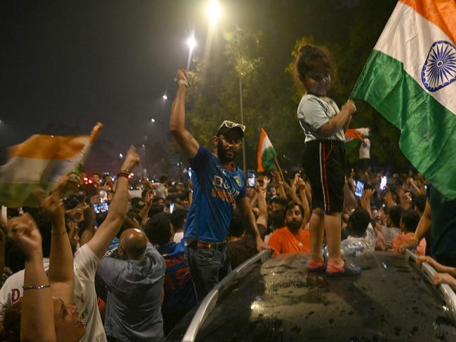 Fans hold Indian national flags as they celebrate India's victory at the 2024 ICC men's Twenty20 World Cup, at India gate in New Delhi on June 29, 2024. (Photo by Arun SANKAR / AFP)