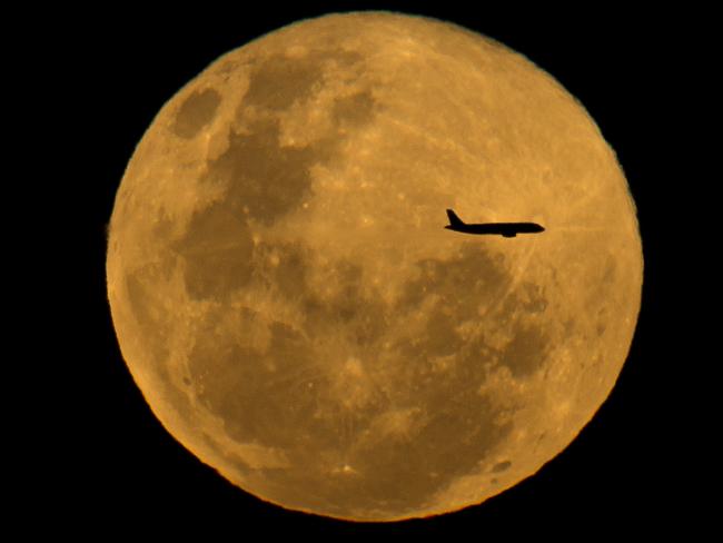 An aircraft flies past the Full Moon. Picture: Jay Town