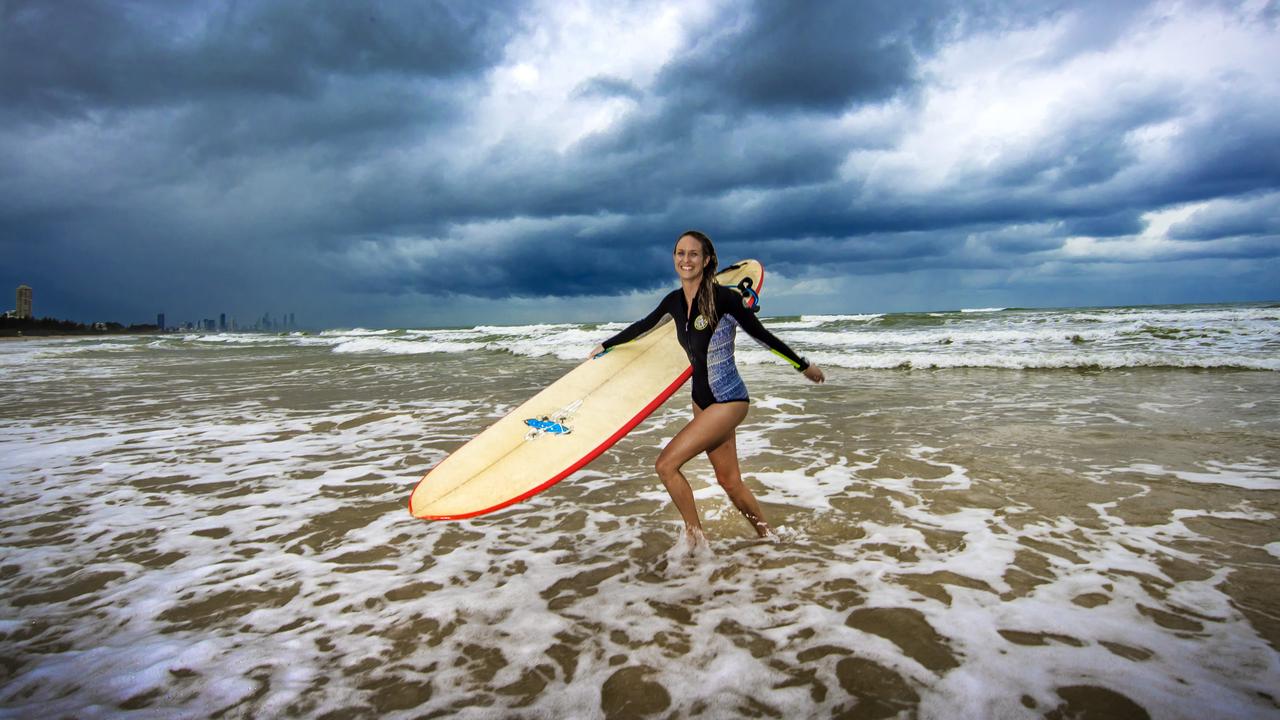 Local surfer Roxy Emberg doesn't let the wet weather stop her from going for a surf at Burleigh Heads beach. Picture: NIGEL HALLETT