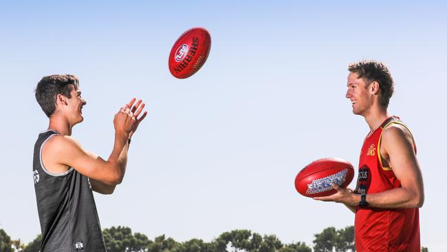 Port Adelaide's Connor Rozee and Gold Coast's Jack Lukosius handballing the football together while obeying social distancing rules. They have been reunited at training because of the AFL, COVID-19 enforced shutdown. Picture: AAP/Russell Millard.