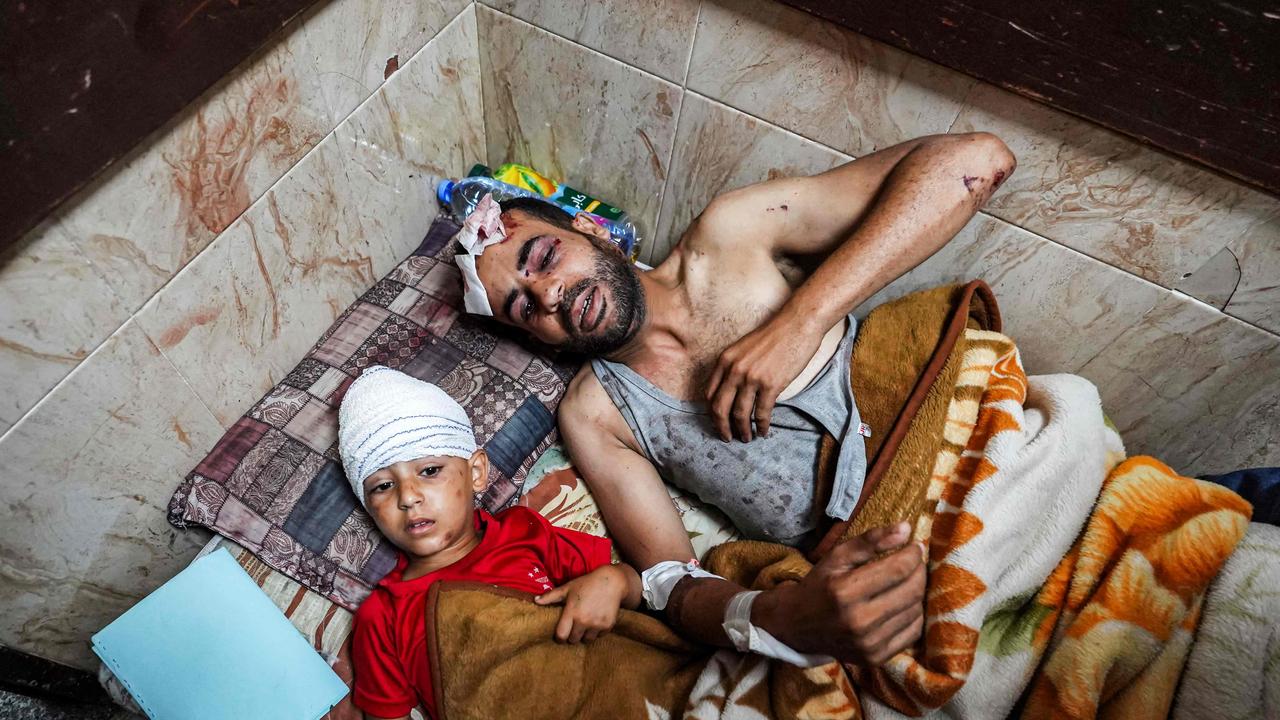 / Youssef Abu Galambo lies with his son Hamza, both injured during Israeli bombardment in al-Bureij in the central Gaza Strip. Picture: AFP