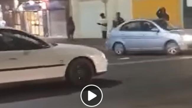 A scene from the footage of the Hyundai Accent, right, hooning dangerously through the streets of the Alice Springs CBD. A passenger (far right) can be seen hanging out of a window while the car speeds through the intersection of Gregory Terrace and Todd Street. Video: Action for Alice 2020 via Facebook