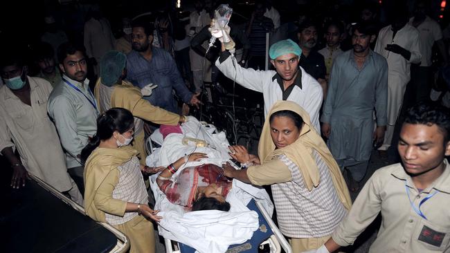 Pakistani relatives and emergency workers carry an injured woman to the hospital in Lahore on March 27, 2016, after at least 56 people were killed and more than 200 injured when an apparent suicide bomb ripped through the parking lot of a crowded park in the Pakistani city of Lahore where Christians were celebrating Easter. / AFP PHOTO / ARIF ALI