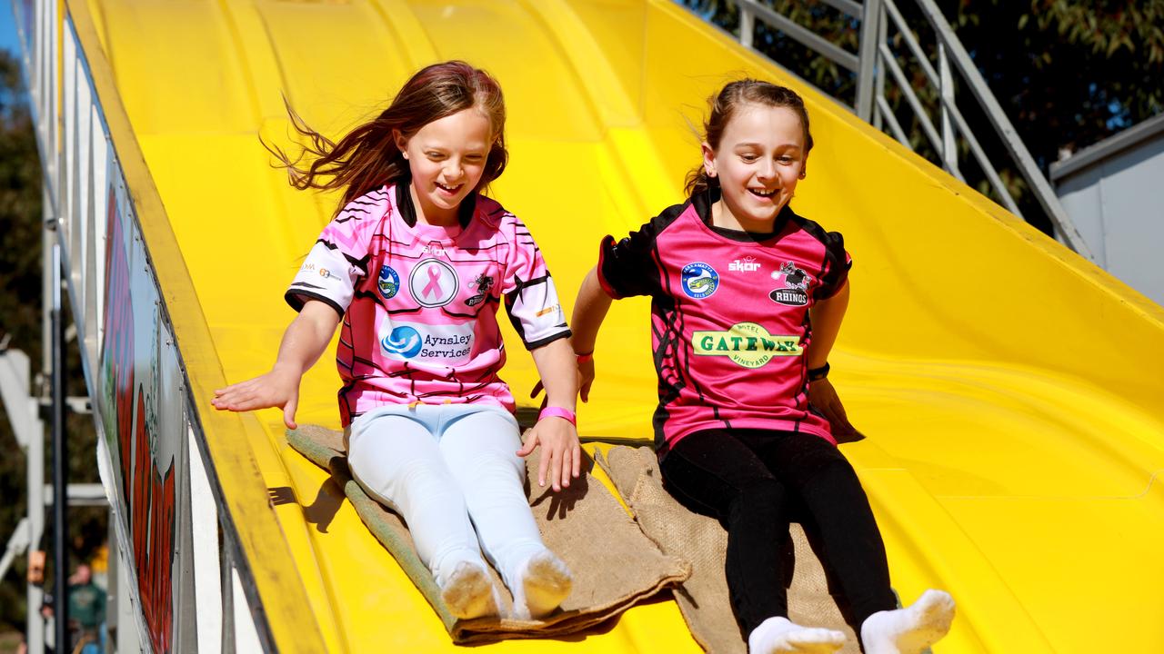 9 year old Ava Swift and her friend 9 year old Matilda Denmeade fly down the super slide at the Rouse Hill Rhinos Pink Day in Kellyville. (AAP IMAGE / Angelo Velardo)