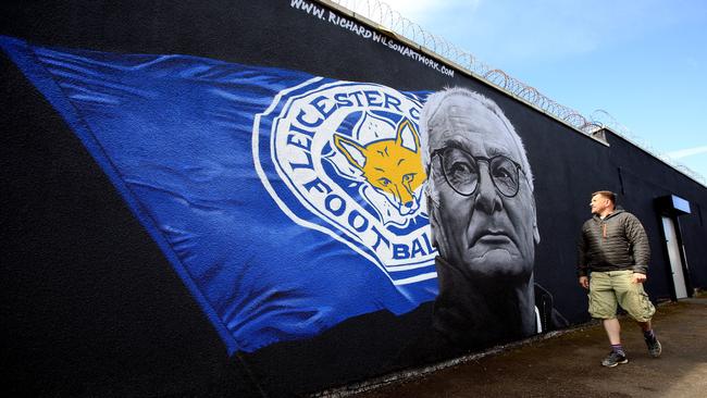 A Leicester City fan walks past street art of Leicester City manager Claudio Ranieri.