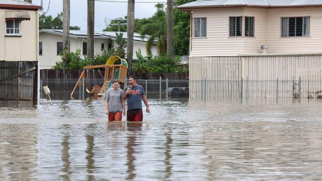 Two people walk through flood waters in Ingham. Pics Adam Head