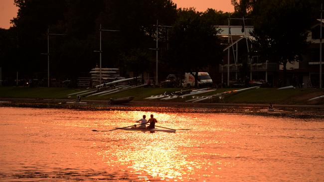 Rowers under an orange glow this morning. Picture: Andrew Henshaw