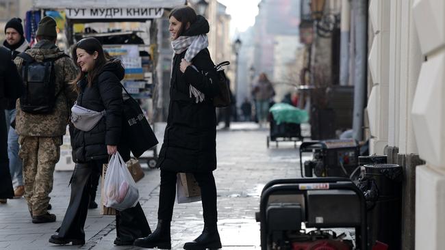 Ukrainians walk past a shop using generators for power. Picture: Getty Images.