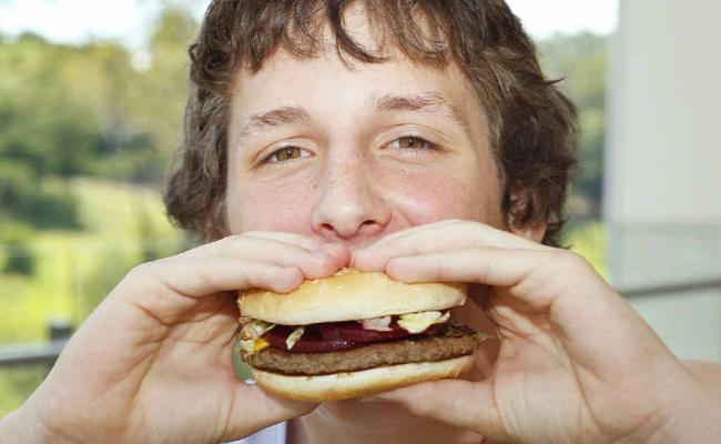 Kyle Grice, 14, of Ipswich tries one of McDonalds McOz Burgers with locally grown beetroot.  . Picture: David Nielsen