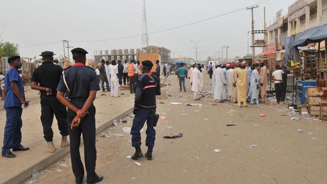 Security officers stand guard at the scene of an explosion at a mobile phone market in Kano, Nigeria on Wednesday. Picture: AP.