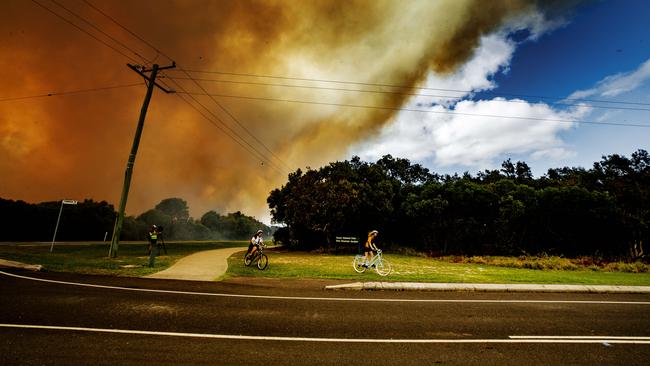 Coolum school kids evacuate on their bikes as a bushfire rages between Coolum and Peregian Beach. Picture: Lachie Millard