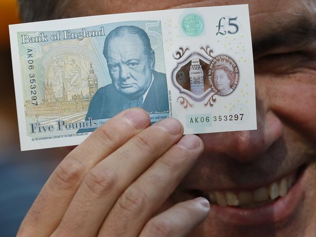 Governor of the Bank of England Mark Carney poses with a new polymer five pound note, at Whitecross Street Market, to promote the launch of the new bank note, in London, on September 13, 2016. The Bank of England will initially issue 440 million of the new polymer £5 notes ($6.7, 5.9 euros) and the old note will cease to be legal tender in May 2017. "We expect polymer notes to last at least two-and-a-half times longer than the current generation of fivers and therefore reduce future costs of production," Carney said. / AFP PHOTO / POOL / STEFAN WERMUTH