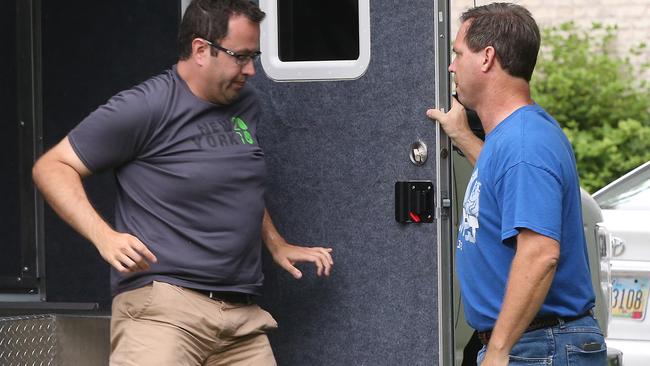 Jared Fogle leaves a police vehicle outside of his home after an FBI raid.