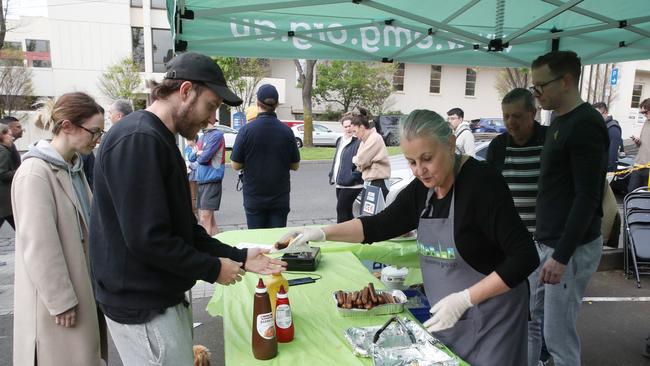 Voters pick up a sausage at the East Melbourne voting booth on Saturday morning. Picture: NCA NewsWire / David Crosling