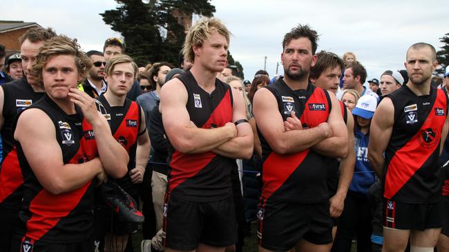 Disappointed Frankston players look on as Hastings celebrates its grand final victory. Picture: Mark Dadswell