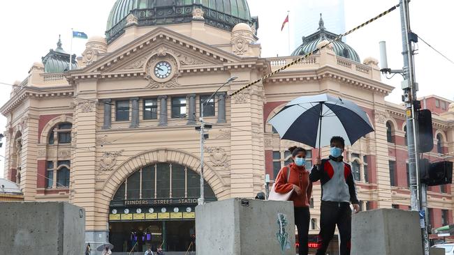 A couple brave the rain near Flinders Street station. Picture: NCA NewsWire/ David Crosling