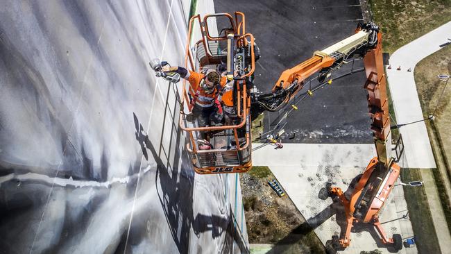 World-renowned large/scale artist Guido van Helten painting the 10-storey building at Southern Cross University Gold Coast campus. Picture: NIGEL HALLETT