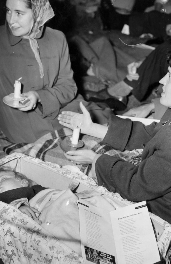 Baby Michael Higgs sleeps as his mother enjoys the 1953 Carols by Candlelight.