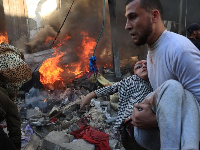 TOPSHOT - A man evacuates a wounded girl after Israeli bombardment in Rafah in the southern Gaza Strip on November 17, 2023, amid ongoing battles between Israel and the Palestinian group Hamas. (Photo by SAID KHATIB / AFP)