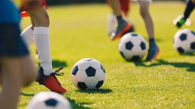 Soccer Football Training for Children. Kids Playing Soccer on Training Football Pitch. Beginner Soccer Drills for Kids. Coach in the Background Coaching Youth Soccer