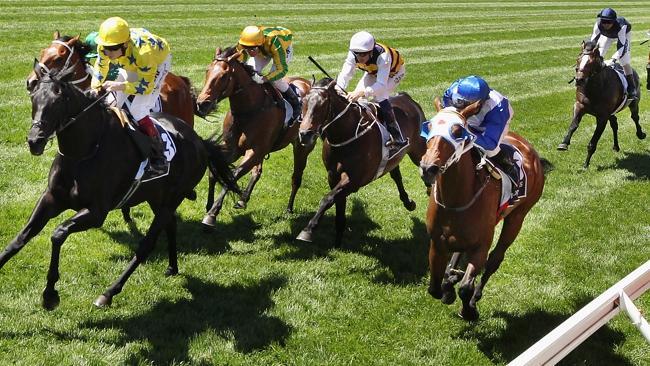 Jockey Jamie Spencer riding Side Glance wins the Mackinnon Stakes from the fast-finishing Dear Demi (blue and white).