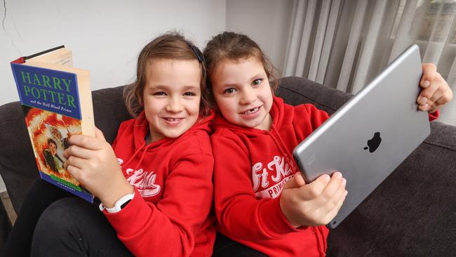 Sisters Ava, 8, and Mae, 6, share books and screen time. Picture: David Caird